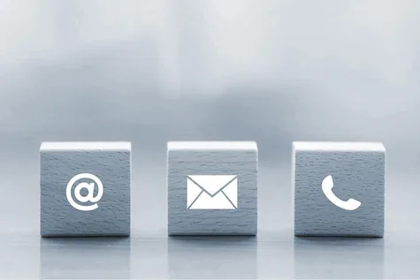 Drei Holzwürfel mit, jeweils mit einem @-Symbol, einem Brief-Symbol und einem Telefon-Symbol