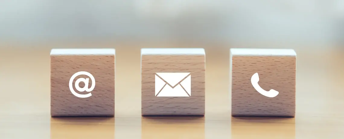 Drei Holzwürfel mit einem @-Symbol, einem Brief-Symbol und einem Telefon-Symbol